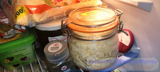 A jar of grated cheddar in the fridge.