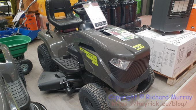 A grey ride-on lawnmower in the shop.