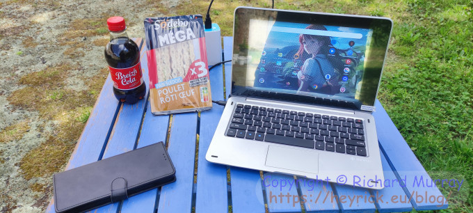 A portable computer on a wooden picnic table.