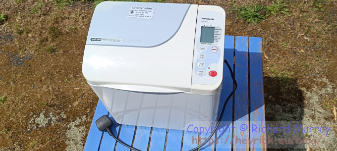 A Panasonic bread maker on a blue table.