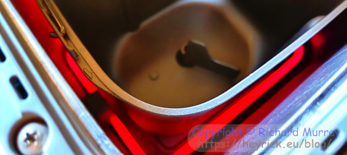 Inside a bread maker with the heater glowing brightly.