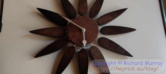 A wooden clock shaped like a flower on a table.