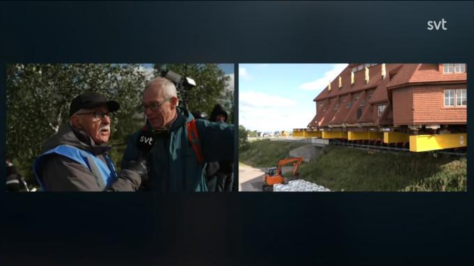 A screenshot of a church being moved and spectators being interviewed.